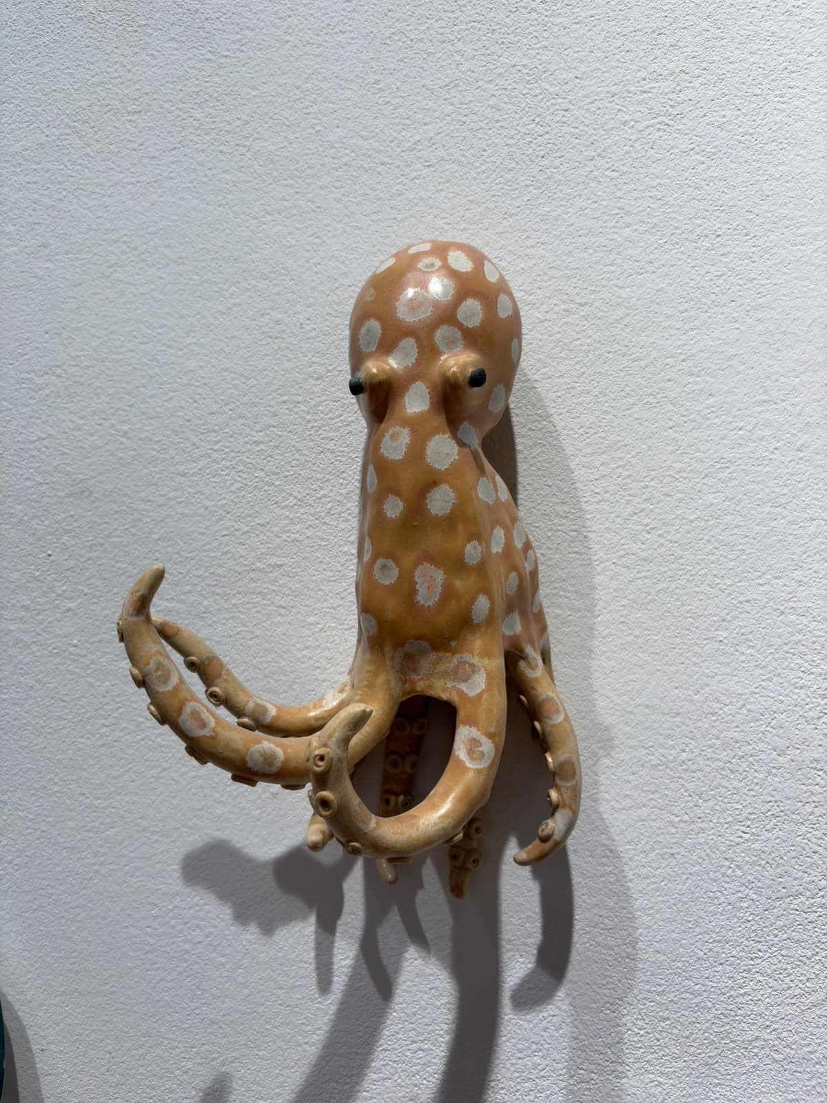 Pulpo de cerámica naranja con lunares blancos en la pared