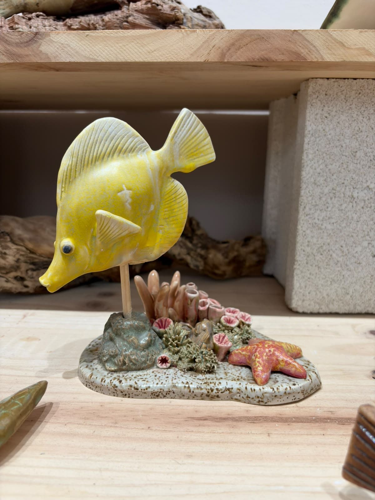 Pez amarillo de cerámica sobre un arrecife con estrella de mar