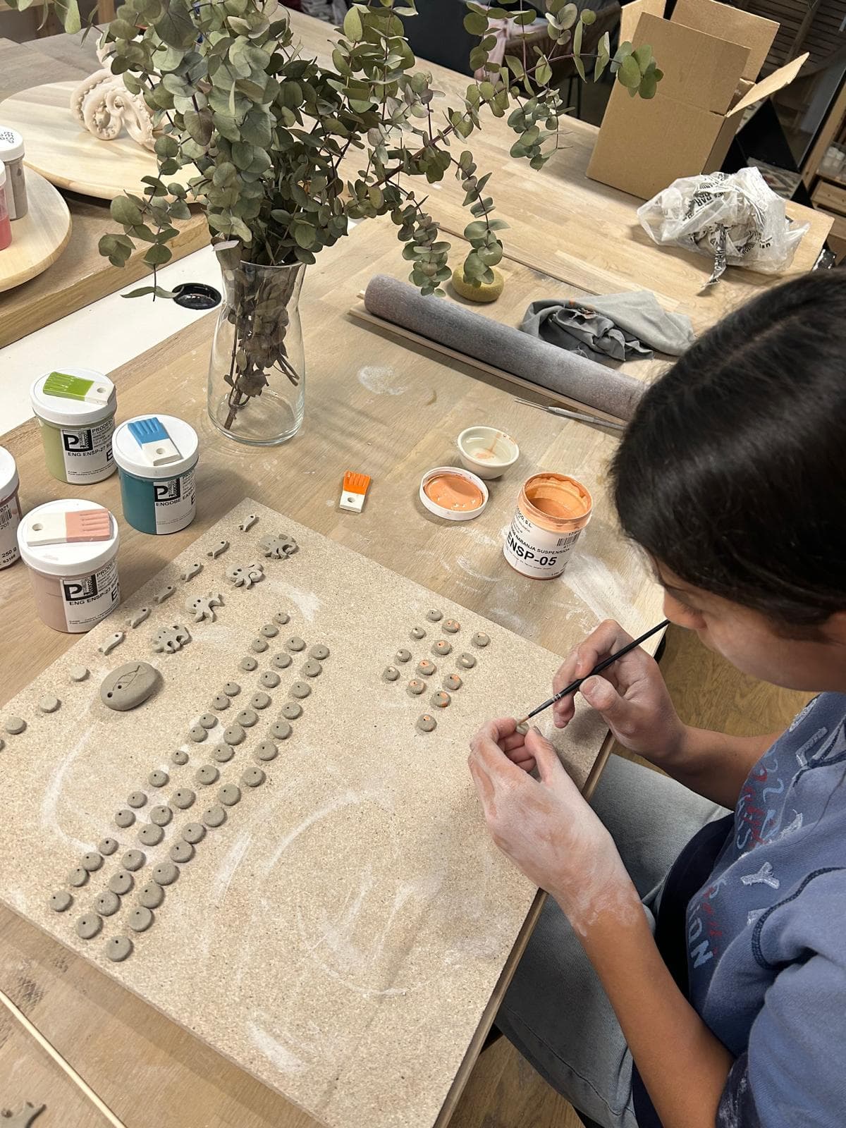 Alumna pintando con pincel piezas pequeñas de cerámica en el taller