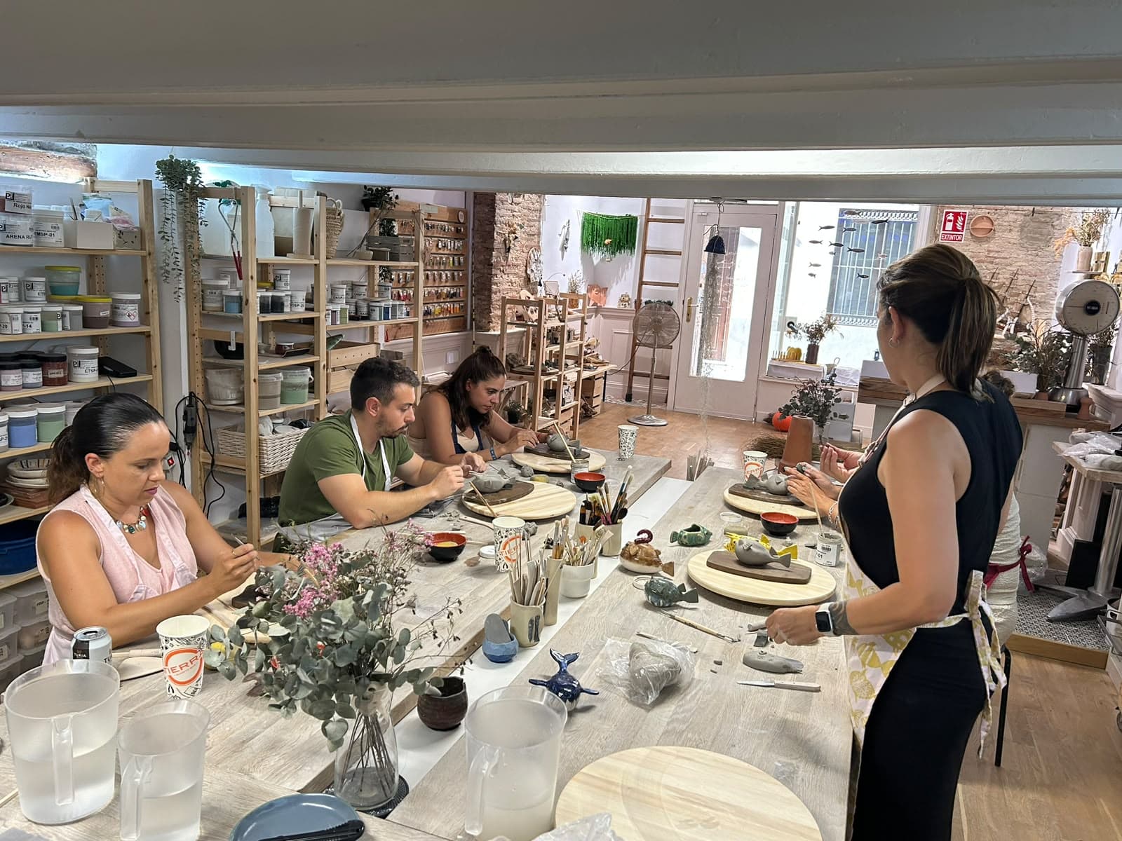 Grupo trabajando el barro alrededor de la mesa del taller con Yoli